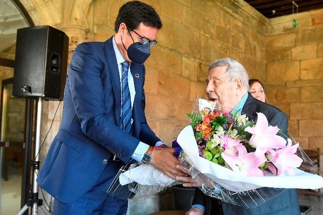 El presidente de Paradores, Óscar López, hace entrega al último superviviente del campo de concentración de un ramo de flores. / Pool EFE